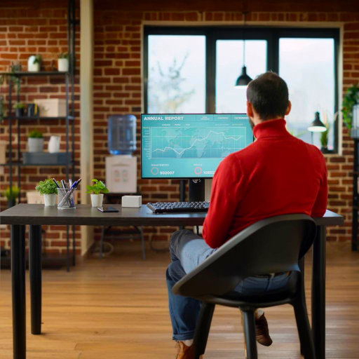 A project manager looking at a computer screen displaying forex exchange charts and financial statistics.